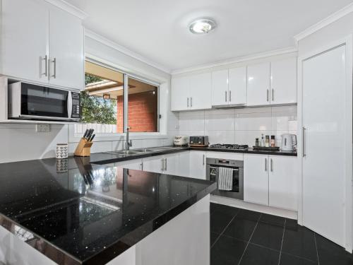 a kitchen with white cabinets and black counter tops at PRIVATE ROOM 1 and PRIVATE ROOM 3 beside Monash University in Clayton in Clayton North