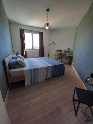 1 dormitorio con cama con sábanas azules y ventana en L'oasis, en Tarbes