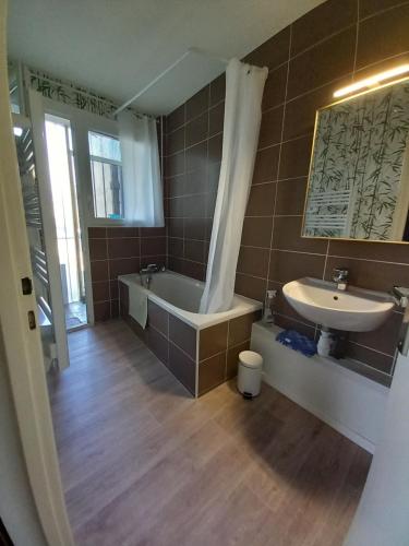 a bathroom with a tub and a sink at L'oasis in Tarbes
