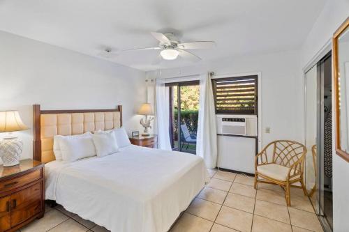 a bedroom with a bed and a table and a chair at Ground floor Banyon Harbor in Lihue