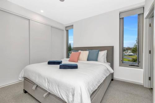 a white bedroom with a large bed with a window at 'Sunset Delight' Hamptons-style Beachfront Living in Adelaide