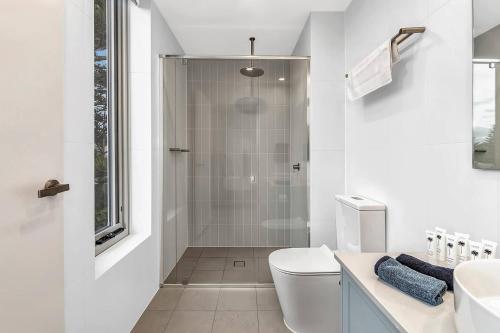 a white bathroom with a shower and a toilet at 'Sunset Delight' Hamptons-style Beachfront Living in Adelaide