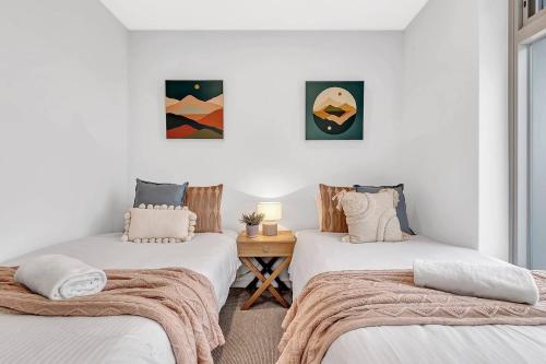 two twin beds in a room with white walls at 'Sunset Delight' Hamptons-style Beachfront Living in Adelaide