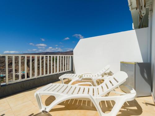 a white chair on a balcony with a view at Incredible Sunsets in Puerto Rico de Gran Canaria