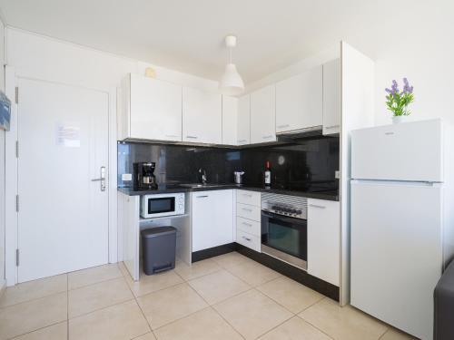 a kitchen with white cabinets and a white refrigerator at Incredible Sunsets in Puerto Rico de Gran Canaria