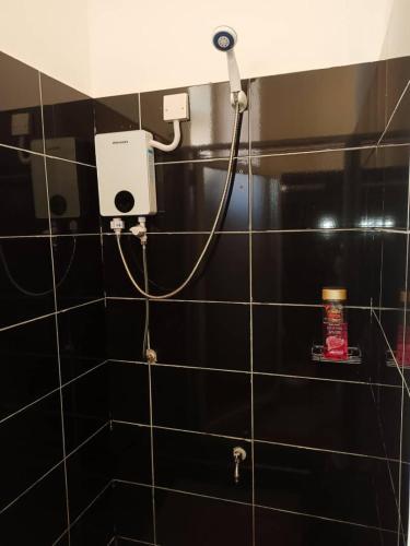 a black tiled bathroom with a hair dryer on a wall at Serene Homes 04 in Kampala