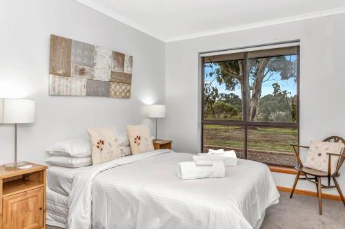 a white bedroom with a bed and a window at Picturesque Vineyard Farmhouse Nestled on 40-Acres in McLaren Vale