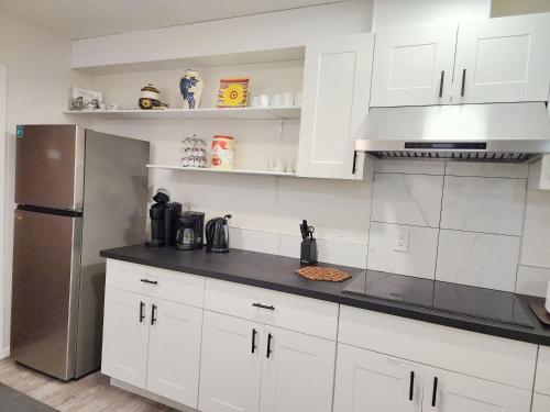 a kitchen with white cabinets and a stainless steel refrigerator at Ocean's Edge Suite in Campbell River