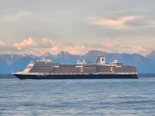 a cruise ship on the water with mountains in the background at Ocean's Edge Suite in Campbell River