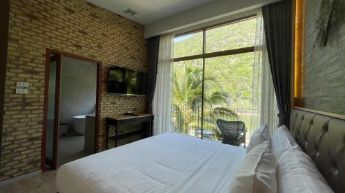 a bedroom with a bed and a large window at La Isla Pranburi Beach Resort in Sam Roi Yot