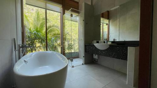 baño con bañera, lavabo y ventana en La Isla Pranburi Beach Resort, en Sam Roi Yot