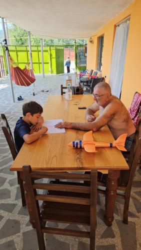 um homem e um rapaz sentados numa mesa de madeira em Guest house lagodekhi em Lagodekhi