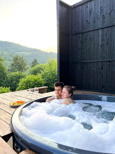 a man and woman sitting in a hot tub at Mirest - котеджі в горах із чаном-джакузі in Slavske