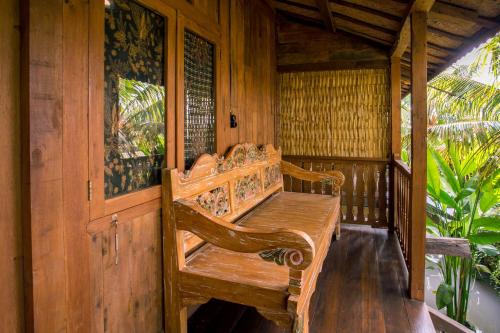 a wooden bench on the porch of a house at Pondok Cap Oleng Guesthouse Canggu by Ecommerceloka in Canggu