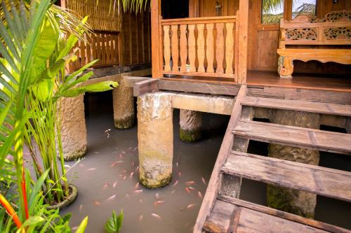 a wooden footbridge in the water with a house at Pondok Cap Oleng Guesthouse Canggu by Ecommerceloka in Canggu