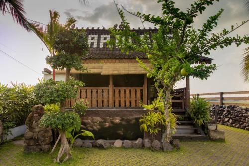 a house in the middle of a garden with trees at Pondok Cap Oleng Guesthouse Canggu by Ecommerceloka in Canggu