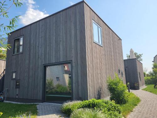 a timber clad house with a large glass door at Les Cubes in Martigny-Ville