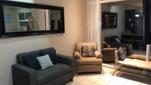 a living room with couches and chairs and a mirror at Ocean View 2 BR Condo in Tijuana