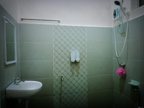 a green bathroom with a sink and a shower at HOMESTAY Duranta Home's in Batu Pahat