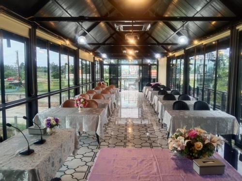 eine Reihe von Tischen und Stühlen in einem Zimmer mit Fenstern in der Unterkunft Bouasavan Hotel and Garden in Savannakhet