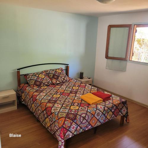 um quarto com uma cama com um edredão colorido e uma janela em fleur de coton location saisonnière em Grand Fond