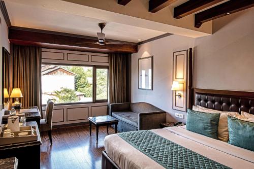 1 dormitorio con cama, sofá y ventana en The Vintage Srinagar at Dal Lake en Srinagar