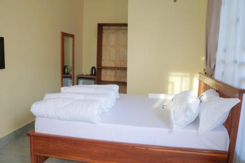 Una cama blanca con cuatro almohadas encima. en Verified Lodge en Dodoma