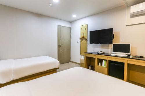 済州市にあるAliba Hotelのベッド2台とテレビが備わるホテルルームです。