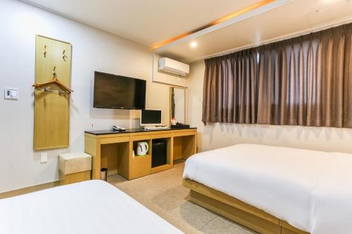 a hotel room with two beds and a television at Aliba Hotel in Jeju