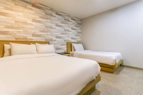 a bedroom with two beds and a stone wall at Aliba Hotel in Jeju