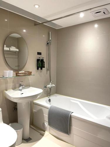 a bathroom with a sink and a tub and a mirror at suye hotel in Taichung
