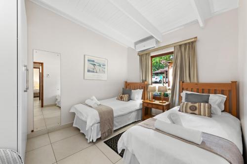 a bedroom with two beds and a window at San Lameer Villa 2707 - 3 Bedroom Classic - 6 pax - San Lameer Rental Agency in Southbroom