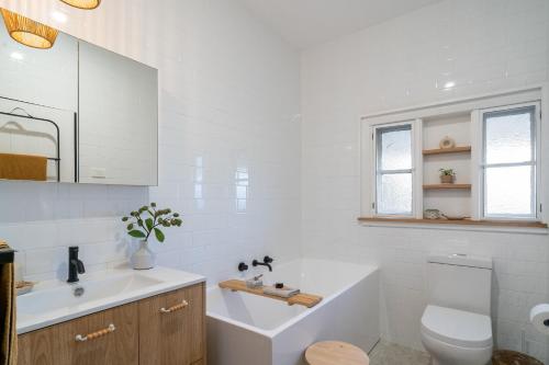 a bathroom with a tub and a toilet and a sink at Maggies The Little Black Cottage - Hunter Valley in Cessnock