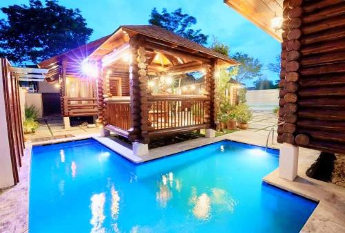 a log cabin with a pool in front of a house at 巴厘岛风格住宿 Muar Balinese Resort in Muar