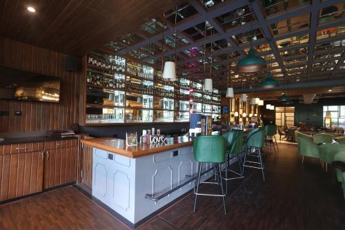 a bar with green chairs in a restaurant at Hotel Polo Towers Agartala in Agartala