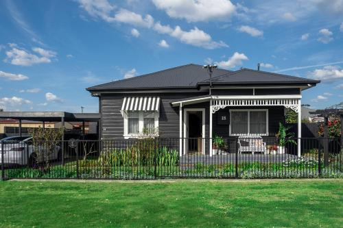 a black and white house with a fence at Maggies The Little Black Cottage - Hunter Valley in Cessnock