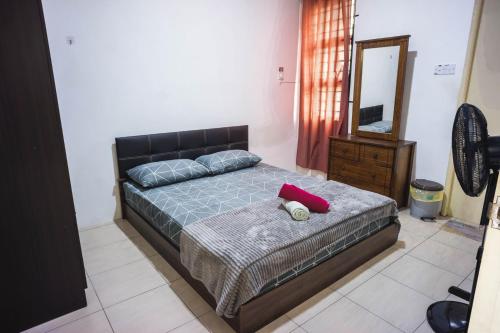 1 dormitorio con cama con almohada roja y espejo en MPE Guesthouse en Kota Samarahan