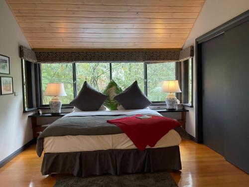 a bedroom with a large bed and a large window at Woodlands rainforest retreat in Narbethong
