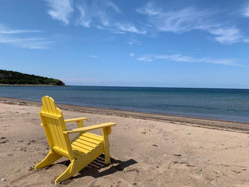 Port Hood的住宿－Colindale Beach Villas，坐在海滩上靠近水面的黄色椅子