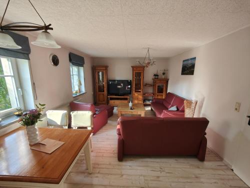 ein Wohnzimmer mit roten Sofas und einem Tisch in der Unterkunft Ferienwohnung Zittauer Gebirge in Waltersdorf