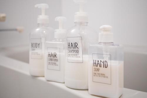 four bottles of hand soap sitting on a shelf at Good Life Apartment in Naha