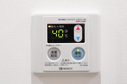 an electronic alarm clock on a white wall at Good Life Apartment in Naha