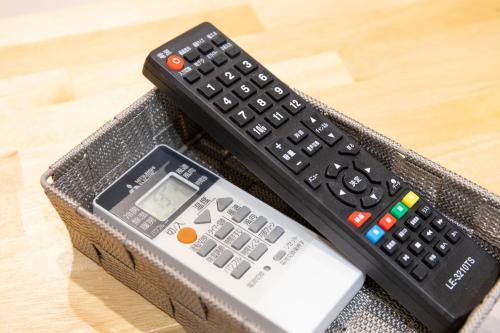 a remote control and a cell phone in a basket at Good Life Apartment in Naha