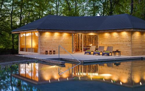 a log cabin with a pool in front of it at Hotel Dębowy Biowellness & SPA Góry Sowie in Bielawa