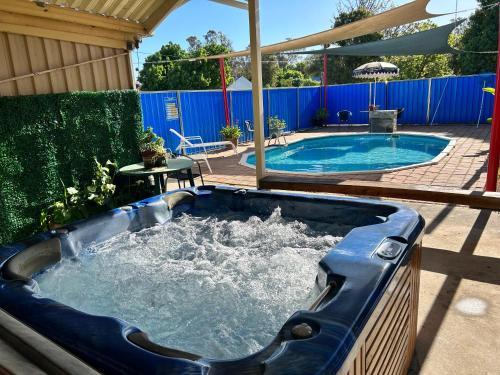 a large hot tub in a backyard with a pool at Acacia Rose Motor Inn in Barham