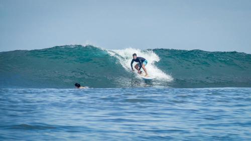 a man riding a wave on a surfboard in the ocean at Surf & Party - Hostel Somewhere Else in Canggu