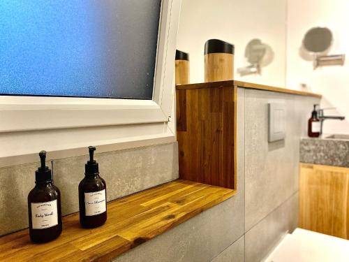 two bottles of wine sitting on a shelf in a bathroom at Grand studio classé 4 étoiles avec jardin et garage vélo, moto in Briançon