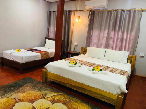 una camera d'albergo con due letti con fiori di Inthila Garden Guest House a Vang Vieng