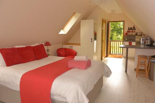 1 dormitorio con 1 cama grande con almohadas rojas en HAYNE BARN ESTATE - Froggies - Independent Self contained studio on private estate en Postling