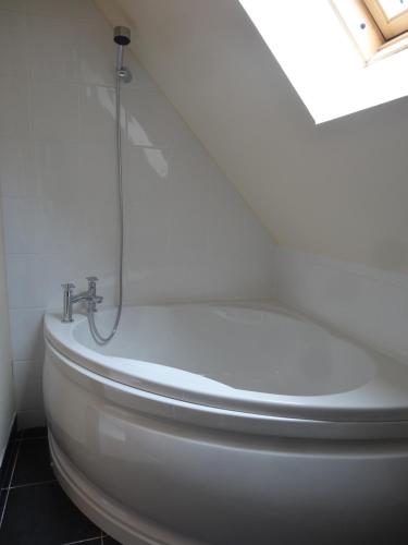 a white bath tub with a shower in a bathroom at HAYNE BARN ESTATE - Froggies - Independent Self contained studio on private estate in Postling